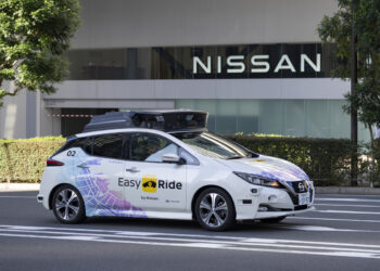 Image of a Nissan vehicle demonstrating autonomous driving capabilities on a busy public road, equipped with advanced sensors and technology.